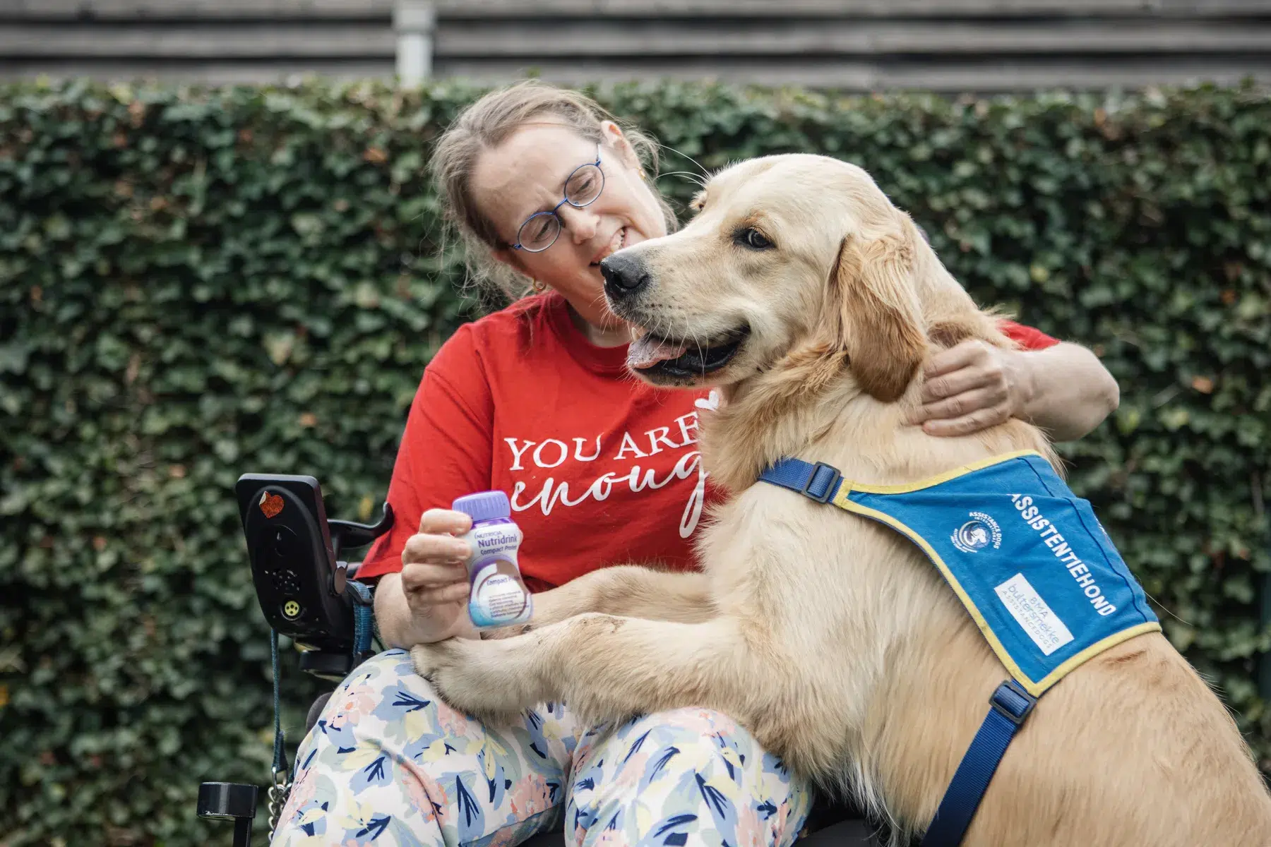 Lid van de patiëntenvereniging Ehlers-Danlos in een rolstoel met een assistentiehond